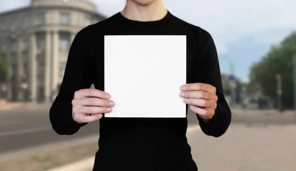 Ένας άντρας που κρατά ένα λευκό φύλλο χαρτί. Κρατώντας ένα φυλλάδιο. Κοντινό u — Φωτογραφία Αρχείου