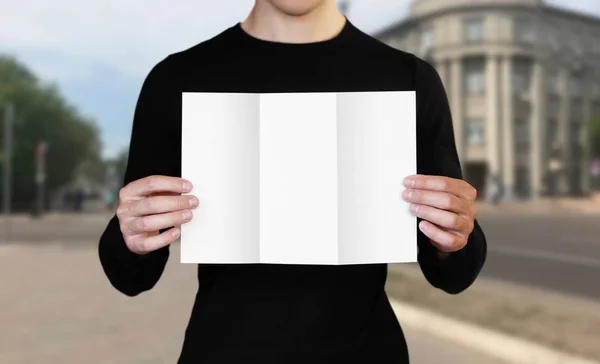 A man holding a white sheet of paper. Holding a booklet. Close u — Stock Photo, Image