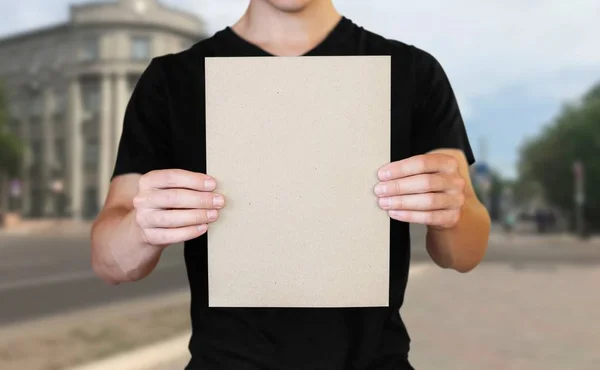 Man showing blank white big A2 paper, covers the face. Leaflet p