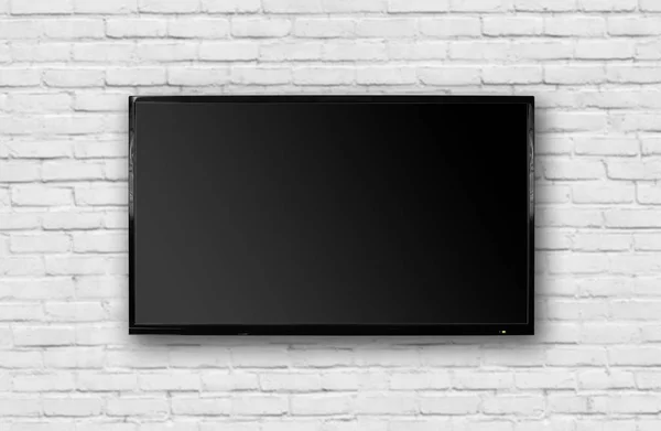 LCD TV with a thin black frame hanging on a white brick wall. Bl — Stock Photo, Image
