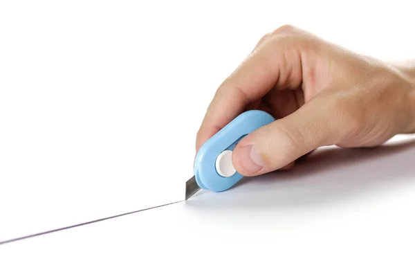 Рука держит небольшой канцелярский нож и режет бумагу. Закрыть — стоковое фото