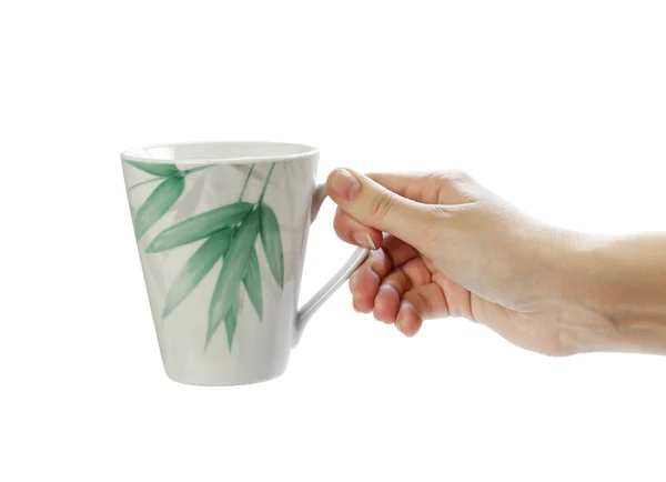 Mão segurando caneca branca com uma imagem de folhas verdes. Fechar . — Fotografia de Stock