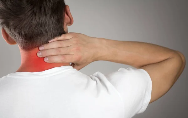 Pain in the neck of a man. Highlighted in red. On a gray background. Close up.