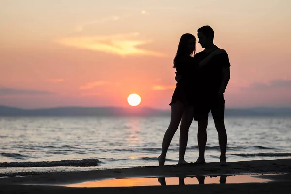 日没時に海の上で若いカップル 夕暮れ時の男と女 — ストック写真