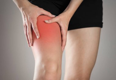 Pain in the leg of a woman. Highlighted in red. On a gray background. Close up. clipart