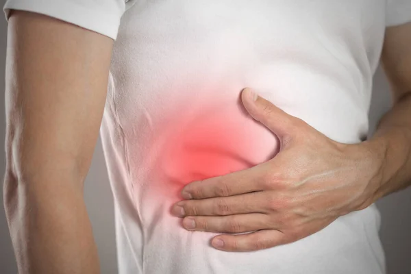 Liver pain in a man. Highlighted in red. On a gray background. Close up.