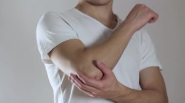 Adamın dirseği ağrıyor, kolunda ağrı var. Kapatın. Gri bir arkaplanda izole edilmiş.