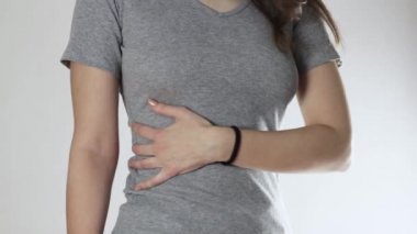 Genç bir kızda karaciğer ağrısı. Kapatın. Gri bir arkaplanda izole edilmiş.