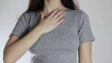 Genç bir kızda boğaz ağrısı. Kapatın. Gri bir arkaplanda izole edilmiş.