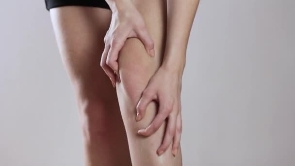 Pain in the knee of a young girl. Close up. Isolated on a gray background. — Stock Video