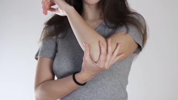 Flickan har ont i armbågen, ont i armen. Närbild. Isolerad på en grå bakgrund. — Stockvideo