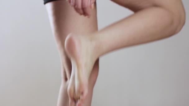 The girl scratches her foot. Itchy leg. Close up. Isolated on a gray background. — Stock Video