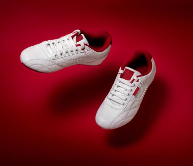 Metin kopyalama yeri olan kırmızı arka plan üzerinde yüzen beyaz spor ayakkabı.