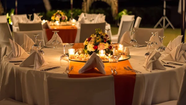Candle lit outdoor table setting at a function.