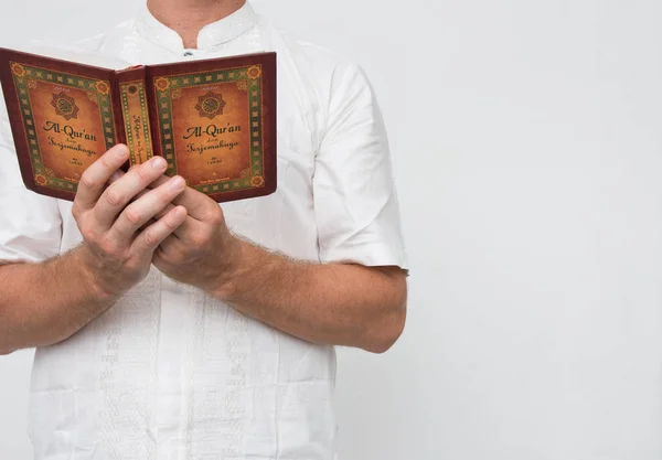 Άνθρωπος φορώντας λευκό στέκεται διαβάζοντας Αλ-Κοράνι με χώρο αντιγραφής. — Φωτογραφία Αρχείου