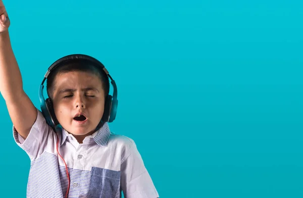 Kleiner Junge mit ausdrucksstarkem Gesicht hört Musik über Kopfhörer — Stockfoto