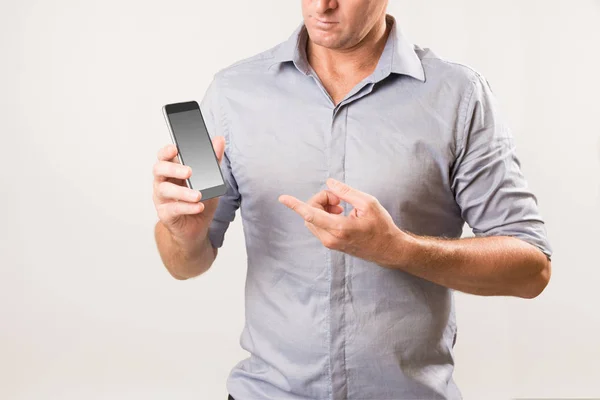 Homem segurando telefone e apontando para a tela com outra mão . — Fotografia de Stock