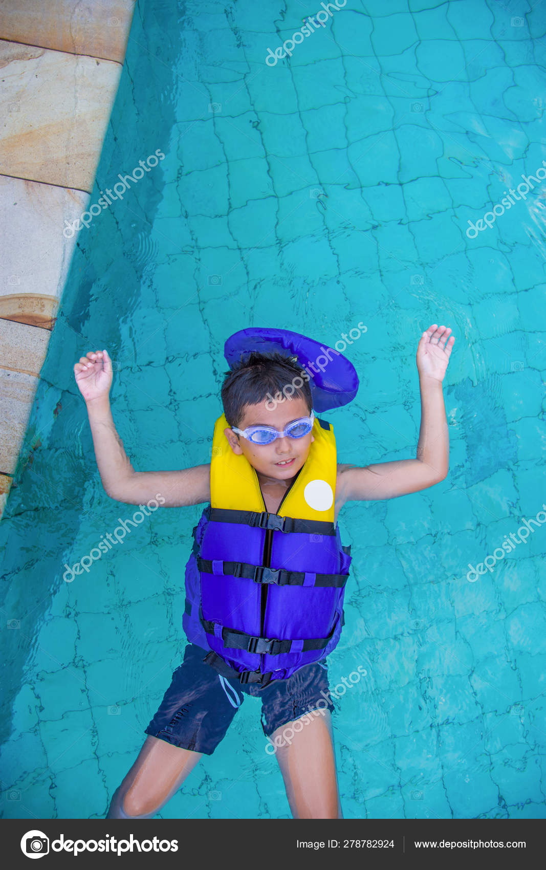 Boy swimming with life vest and googles on shot from above childhood