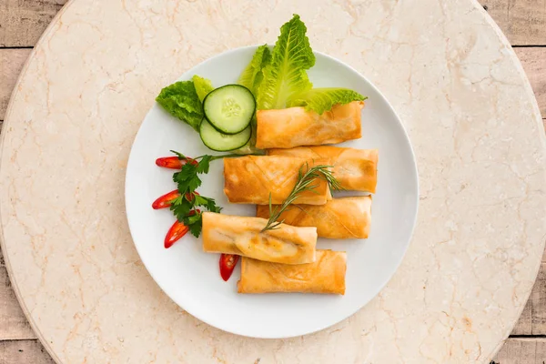 Tasty looking spring rolls served on a round plate with garnish - food concept flat lay image with copy space for text. — Stock Photo, Image