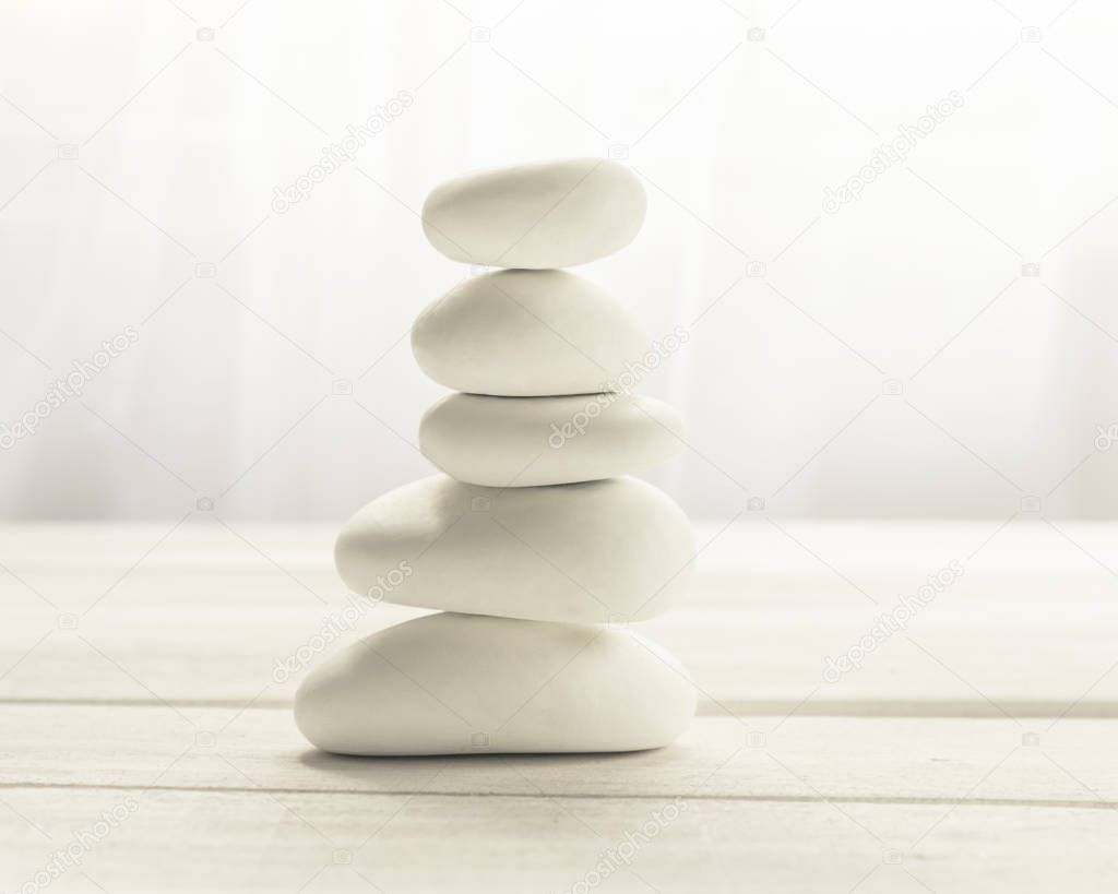Stacked white stones on white background - Lifestyle and alternative health concept image with copy space for text.