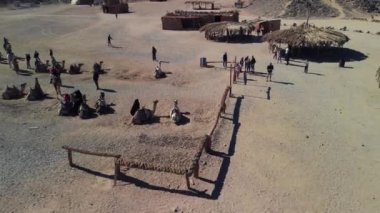 Sahra Çölü 'nün en üst manzarası, çöl dağları. Ahşap Bedevi evleri. Kumlar. Köyde turistler dolaşıyor..