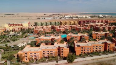 Otelin üstünden ve Hurghada yakınlarındaki çölden uçuyor. Konut manzarası, turistler için yüzme havuzları. Çölün ortasında güzel bir bölge. Oasis. Sahilin üst manzarası, sahil, kristal berrak deniz. Mısır.
