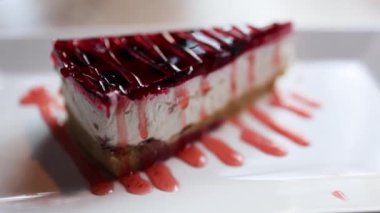 Videoda parlak kırmızı jöle kaplamalı bozulmuş bir cheesecake var. Kremalı peynirli kek ve canlı, parlak ahududu ya da çilekli jelatin karışımı..