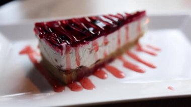 Videoda parlak kırmızı jöle kaplamalı bozulmuş bir cheesecake var. Kremalı peynirli kek ve canlı, parlak ahududu ya da çilekli jelatin karışımı..