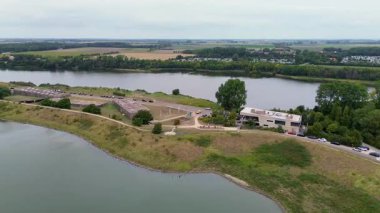 Tarihi binalar, park edilmiş arabalar, tarlalar ve yeşil ağaçlarla dolu bir nehir, göl ve kırsal alan manzarası, doğa, mimari ve barışçıl bir kırsal alan..