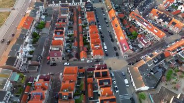 Turuncu çatıları, dar caddeleri ve park halindeki arabaları olan, geleneksel mimarinin sergilendiği büyüleyici bir Avrupa kasabası manzarası..