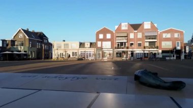 Dik çatılı evleri ve merkezi kilise kulesi olan bir Avrupa kasabasının havadan görünüşü. Açık mavi gökyüzünün altında beyaz ve kahverengi cephelerin karışımı büyüleyici, geleneksel bir atmosfer yaratır..