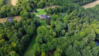 Birden fazla binaya, manikürlü çimenlere ve çevreleyen ormana sahip büyük bir arazinin havadan görüntüsü. Gözlerden uzak yerleşim, mimariyi doğal manzarayla harmanlıyor..