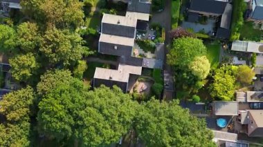 Karanlık çatılı evleri, bahçeleri, bahçeleri ve ağaçlarla kaplı patikaları olan planlı yerleşim yerlerinin hava manzarası. Yerleşim doğal yeşillikle özel açık alanları birleştirir.