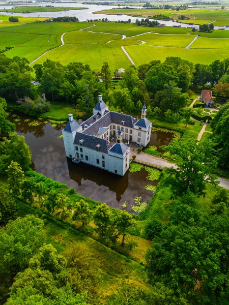 Kuleleri olan büyük tarihi bir malikane, bir hendekle çevrili bir adada, köprülerle bağlanmış, yemyeşil ağaçların, açık arazilerin ve sakin bir kırsal bölgedeki dolambaçlı yolların ortasında..