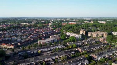Turuncu çatıları, yoğun evleri ve yeşillikleri olan temiz mavi gökyüzü altında denize ve kırsala doğru uzanan Avrupa kıyı kasabasının havadan görünüşü.