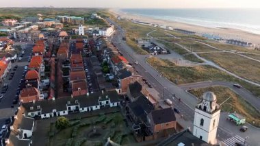 Katwijk aan Zee, Güney Hollanda, Hollanda - 09.06.2025: Kırmızı çatılı evler, tarihi bir kilise, kumlu kum tepeleri, plaj kulübeleri ve sakin deniz manzaralı deniz manzarası
