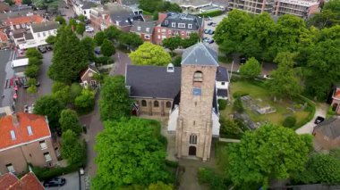Evler, ağaçlar ve dar sokaklar ile çevrili merkezi taştan bir kilise ve uzun çan kulesiyle tarihi cazibeyi barışçıl bir kırsal alan ile harmanlayan tuhaf bir kasabanın havadan görünüşü..