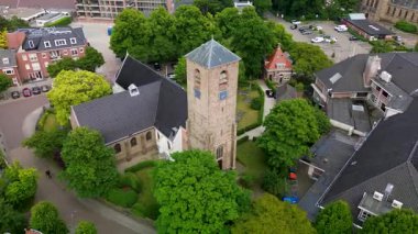 Evler, ağaçlar ve dar sokaklar ile çevrili merkezi taştan bir kilise ve uzun çan kulesiyle tarihi cazibeyi barışçıl bir kırsal alan ile harmanlayan tuhaf bir kasabanın havadan görünüşü..