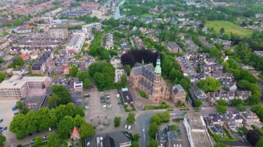 Ağaçlar, yollar ve karışık kullanım binalarıyla çevrili yeşil kulesi olan Gotik bir kilisenin havadan görünüşü. Taş mimarisi bu iyi korunmuş kentsel alanda göze çarpıyor..