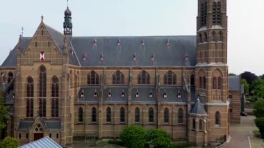Ağaçlar, yollar ve karışık kullanım binalarıyla çevrili yeşil kulesi olan Gotik bir kilisenin havadan görünüşü. Taş mimarisi bu iyi korunmuş kentsel alanda göze çarpıyor..
