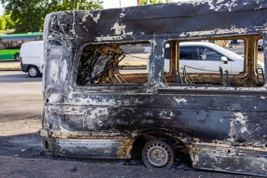 - Savaş. Rus hava saldırılarının barışçıl bir Ukrayna şehrine yaptığı saldırıdan sonra. İçi yanmış bir minibüs, eritilmiş lastikler, kaldırımda açık koltuk çerçeveleri, arabalar, ağaçlar ve arkasında trafik..