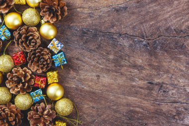 Çam kozalakları, kırmızı şerit üzerinde hediye kutusu ile Noel ve yeni yıl arka plan Xmas süslemeleri ve çam dalları, düz altın top yatıyordu, ahşap bir selamlama metni için boş alan. 