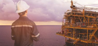 Petrol ve gaz iş kavramı için offshore petrol ve gaz platform arka plan ile tablet kullanarak platform veya bitki mühendis veya teknisyen adamın güvenlik kask ile çift pozlama işletilen.