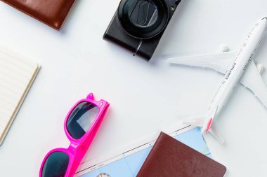 Yaz tatili için seyahat aksesuarı kostümü konsepti. Pasaportlar, bavullar, harita, akıllı telefon, güneş gözlükleri, kamera, not defteri, beyaz kot pantolon.