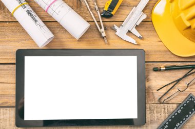 Mimar İşyeri ve teknoloji. Beyaz boş ekran ile tablet, inşaat planları proje ve mühendislik araçları ahşap masa üzerinde alanı kopyalayın, görünümü top