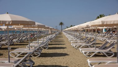 Larnaca, Kıbrıs, Makenzie beach. Boş şezlong ve şemsiyeler kum üzerinde