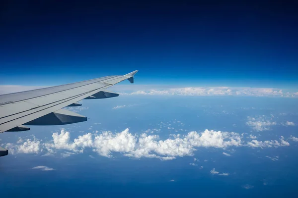 澄んだ青い空を背景に飛行機の翼 飛行機窓の外を見る — ストック写真