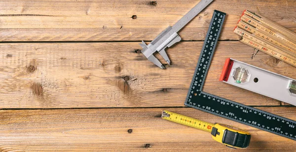 Carpentry tools. Measure tape, spirit level and rulers on wooden background, copy space, top view
