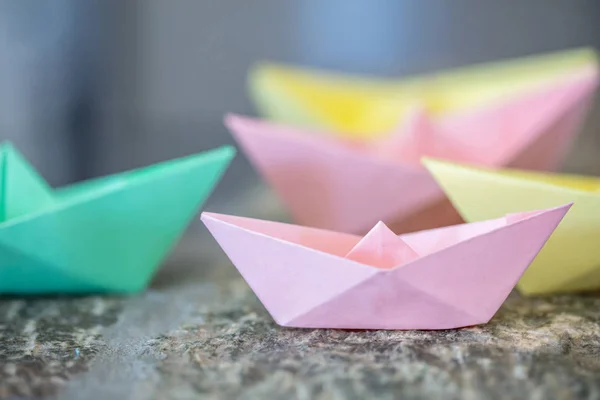 Pastel colored paper folded, origami, boats on a rock