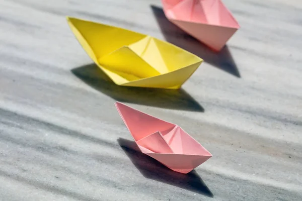 Pink and yellow paper folded, origami, boats on a rock, copy space